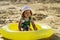 A small beautiful child in a hat is sitting in a small pool