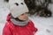 A small beautiful cute child in warm clothes and a knitted hat with a snowflake stuck to his lip stands with closed eyes and a