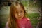 A small, beautiful girl in pink clothes walking in the Park near a flowering tree