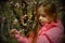 A small, beautiful girl in pink clothes walking in the Park near a flowering tree