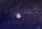 Small beautiful shiny snowflake dropped on a warm lilac knitted