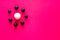 Small black balls surrounding a large white plasticine ball on pink vibrant background. Concepts of bullying and racism, social