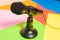 Small black desk microphone with cable and low stand on a multicolored table. Modern style, Communication concept