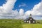 Small black wooden church on green hills Norway tundra