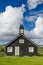 Small black wooden church on green hills Norway tundra