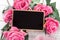 Small blank chalkboard for Valentine`s or mother woman day. Background with pink roses.