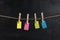Small blank multicolored paper hang with clothespins on rope on black background. Copy space. Place for your text