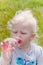 Small blond girl drinks water from a bottle, a close up