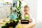 a small blonde girl in an apron is engaged in planting seeds for seedlings, smiling, looking at the camera, the concept