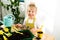 a small blonde girl in an apron is engaged in planting seeds for seedlings, smiling, looking at the camera, the concept