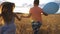 Small blonde girl and red-haired boy holding hands of each other and running through wheat field. Couple of little kids