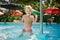 small blonde girl smiles holds pole in shallow water of pool