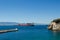 Small blue bay and empty cargo ship on the horizon, Gibraltar.