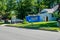 A small blue dumpster is seen in the driveway in front of a house