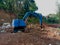 A Small Blue Excavator Seen From The Right Side Above The Ground Being Leveled