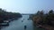 Small blue ferryboat floats on Nerul river in Aguada, Goa, india. A crowd of people on boat and on shore. Aerial view.