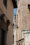 Small blue sky in gap between typically tall European buildings in narrow street