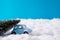 Small blue toy car carrying fir green tree for christmas party celebration drive snowy road under blue sky background