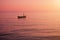 Small boat anchored in the calm sea in colorful sundown