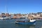 Small boat leaving Arbroath Harbour, Arbroath, Angus, Scotland with several other small boats and yachts moored in the harbour in