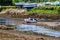 Small boat next to an orange buoy in Clifden Bay at low tide, boats out of the water on the shore