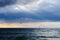 Small boat with a sail on the sea under the stormy sky