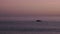 Small boat sails on the calm sea after sunset