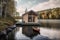 A small boat sits in the water next to a house. AI generative image. Tiny house, houseboat.