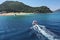 Small boat with tourists heading to iconic small uninhabited island of Marathonisi featuring clear water sandy shore and natural