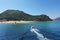 Small boat with tourists heading to iconic small uninhabited island of Marathonisi featuring clear water sandy shore and natural