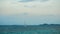 A small boat yacht sailing in the middle of sea with small island in distance as background