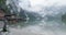 Small boathouse with wood pier and boats on Braies lake with cloudy weather.summer adventure journey in mountain nature