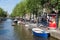 Small boats in canal with historic mansions in Amsterdam