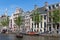 Small boats in canal with historic mansions in Amsterdam