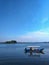 Small boats and fishermen stop in the middle of a calm lake in a monochromatic twilight