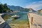 small boats moored in Aegean sea blue lagoon with mountainous islands around, beach at background and turkish flag at top of hill