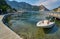 small boats moored in Aegean sea blue lagoon with mountainous islands around, beach at background and turkish flag at top of hill