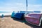 Small boats moored on shore against wall with ocean and sky in background