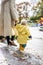 Small bond infant boy wearing yellow rubber boots and yellow waterproof raincoat walking in puddles on a overcast