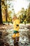 Small bond infant boy wearing yellow rubber boots and yellow waterproof raincoat walking in puddles on a overcast rainy