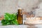 Small bottle with essential mint oil and wooden hair brush on the old wooden background. Fresh spearmint leaves close up.