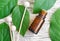 Small bottle of essential oil, diffuser reeds and fresh leaves over wooden background. Aromatherapy and spa concept.