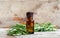 Small bottle of essential rosemary oil on the old wooden background. Aromatherapy, spa and herbal medicine ingredients.
