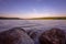 Small boulders submerged in water of a lake on a lakeshore at dusk