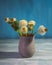 A small bouquet of fluffy dandelions in a gray clay vase on a wooden table