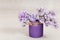 Small bouquet of lilac in purple vase. Fresh flowers lilac close up
