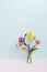 Small bouquet of miniature wildflowers in little cute bottle on pink and blue background, copyspace for summer design
