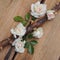 Small bouquet of white roses on thorny branches on a wooden background