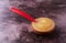 A small bowl filled with sugar free applesauce with a spoon in the food on a maroon background