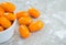 Small bowl overflowing with orange grape tomatoes on a gray marble background